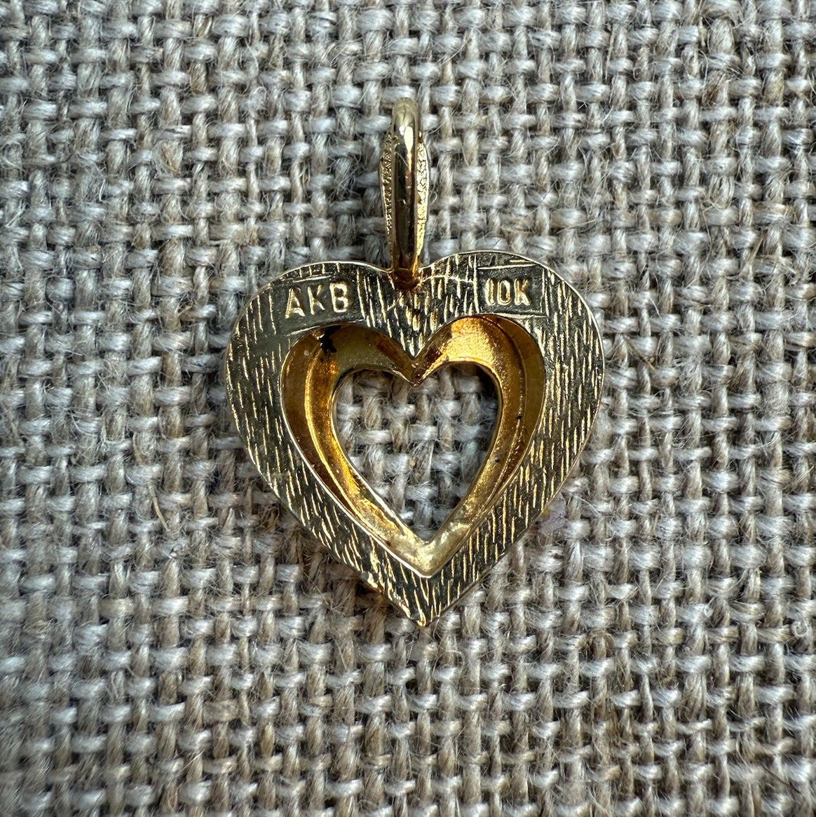 Gold heart-shaped pendant on a textured fabric background