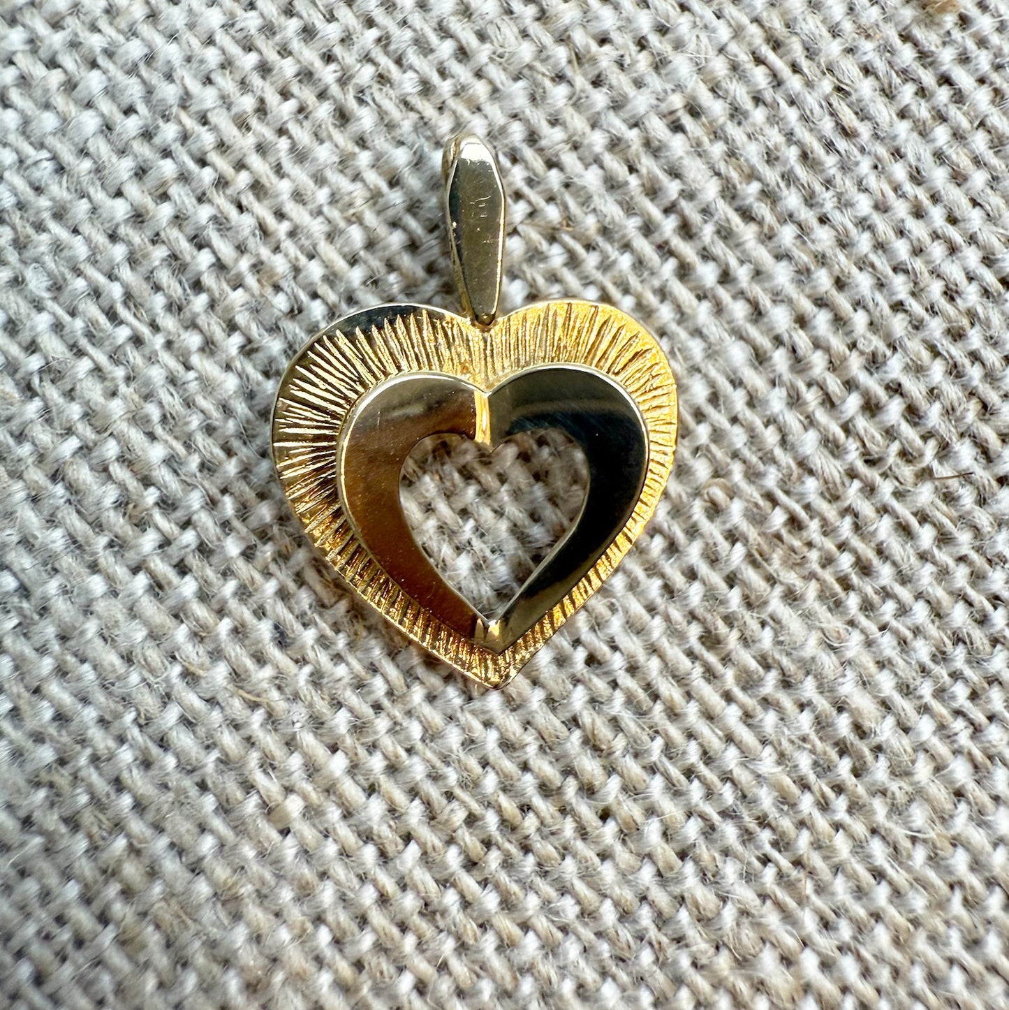 Gold heart-shaped pendant on a textured fabric background