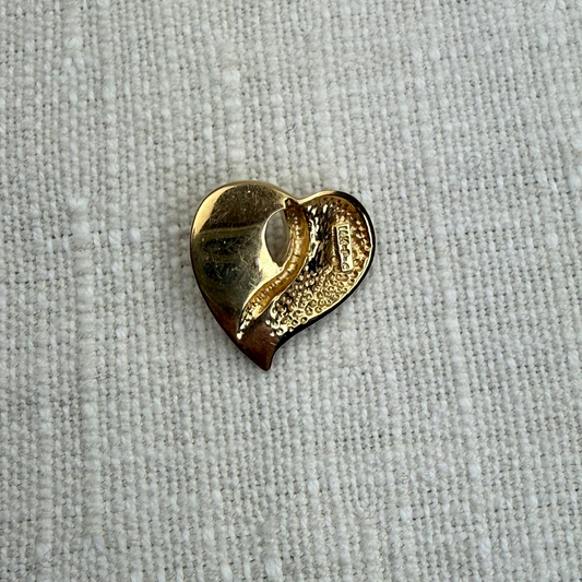 Gold heart-shaped object on a textured gray background