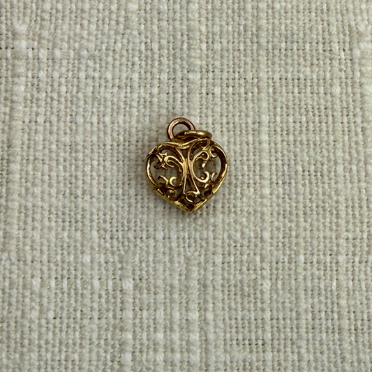 Gold heart-shaped charm on a textured beige fabric background