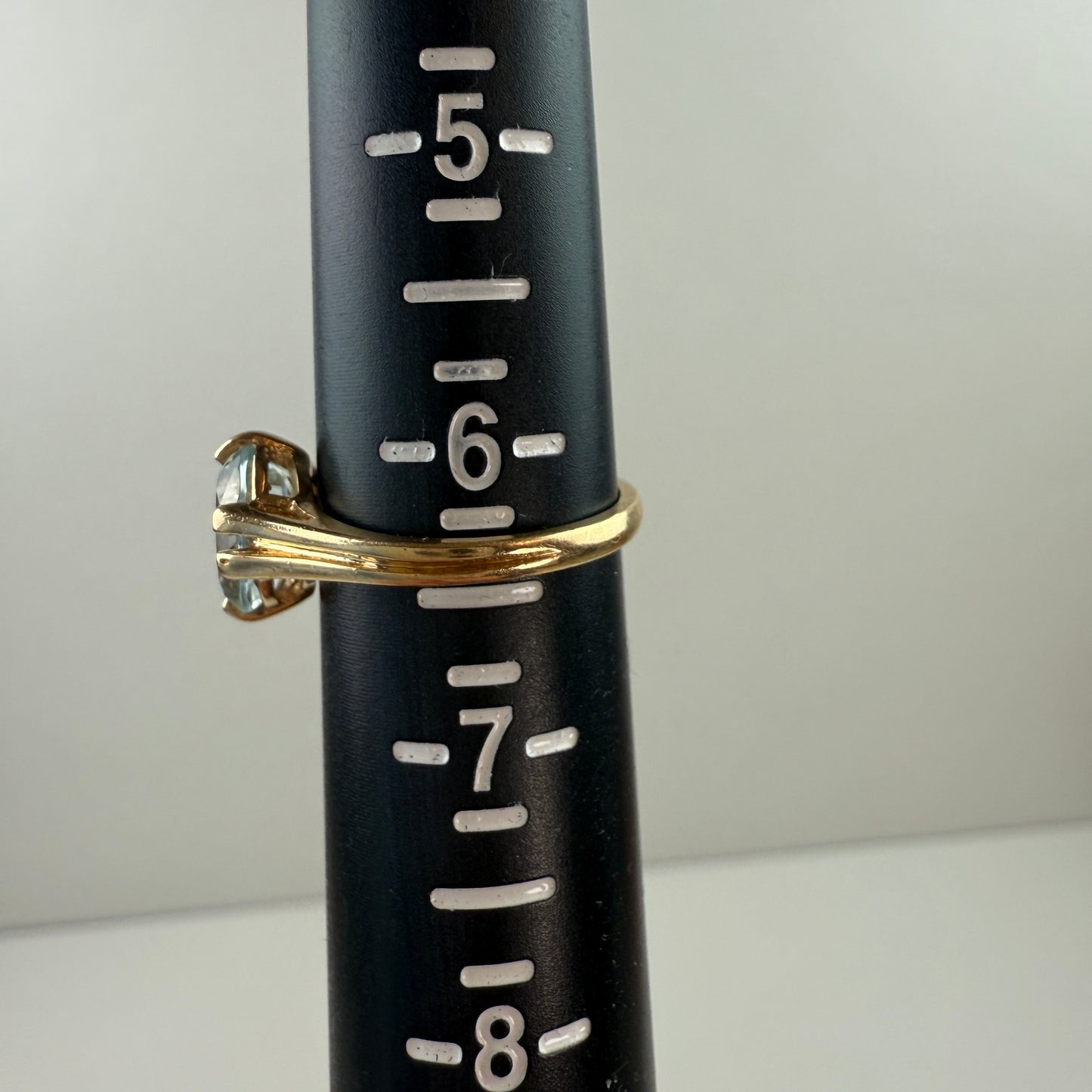 Black measuring tool with gold ring and clear gemstone on a white background