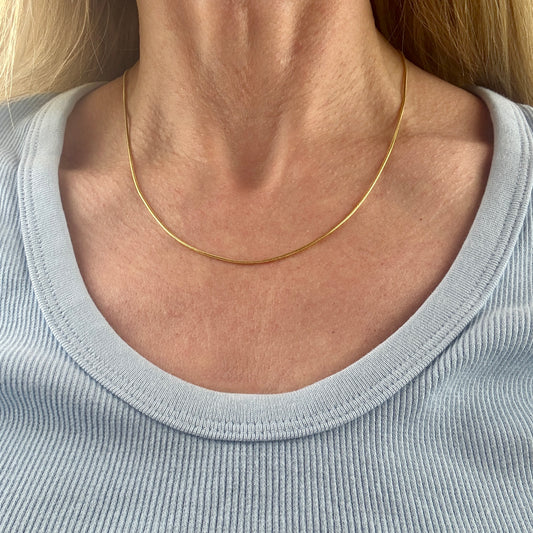 14K gold necklace worn by a person with a light blue shirt