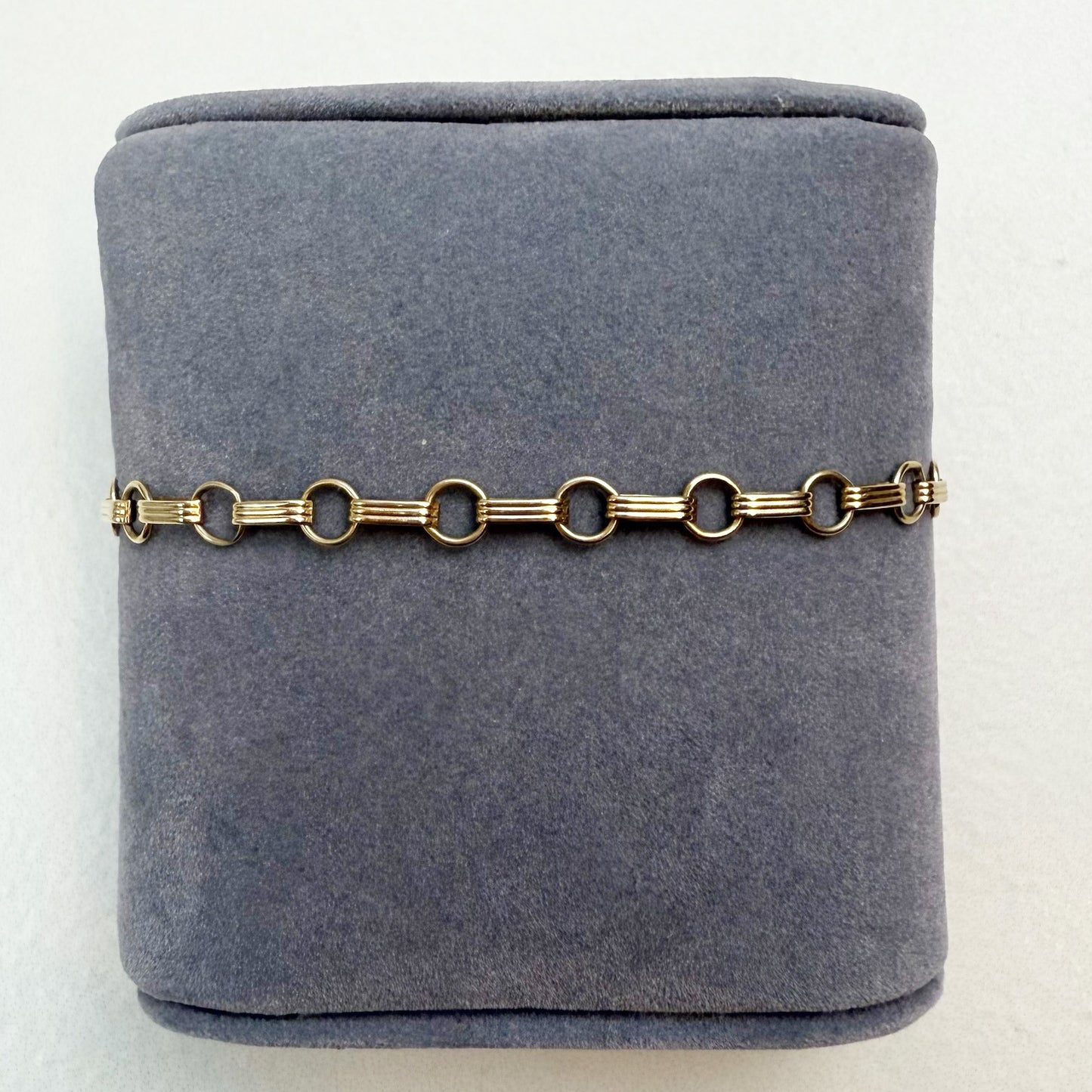 Gold chain bracelet on a gray velvet jewelry box