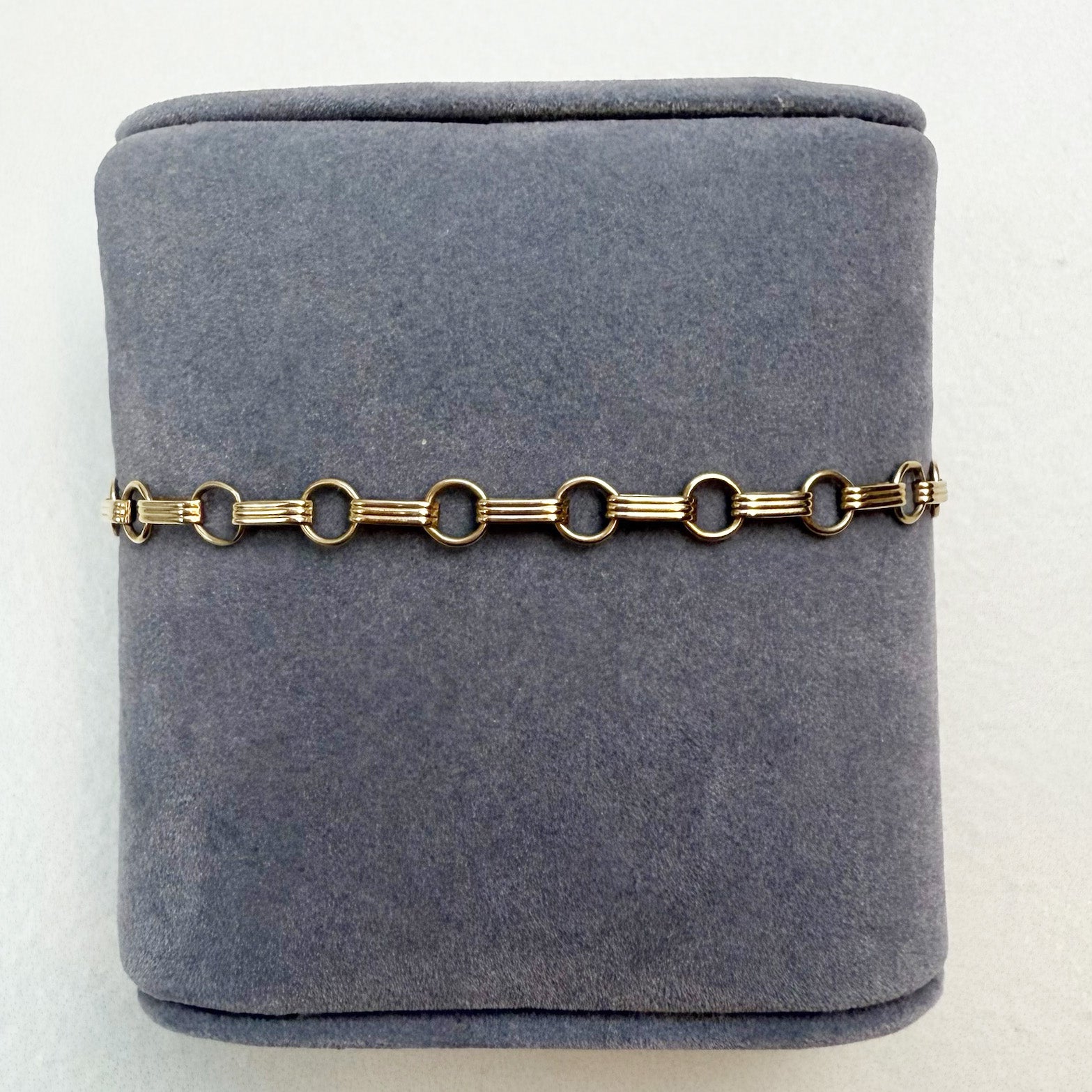 Gold chain bracelet on a gray velvet jewelry box
