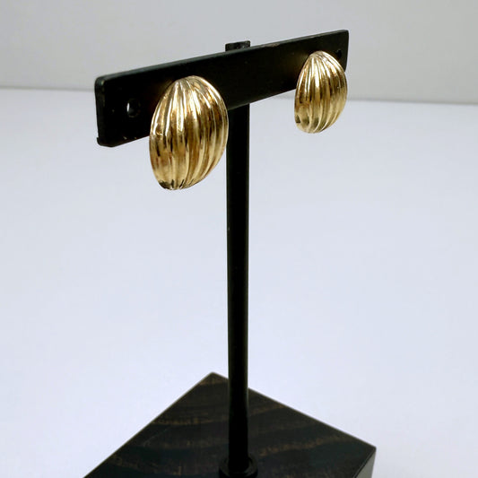 Gold earrings on a black earring stand against a white background