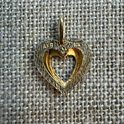 Gold heart-shaped pendant on a textured fabric background