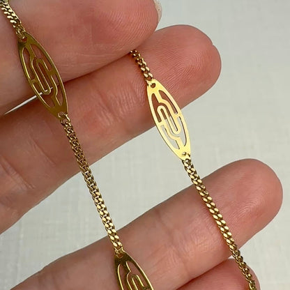 Gold chain bracelet on a hand with a plain background