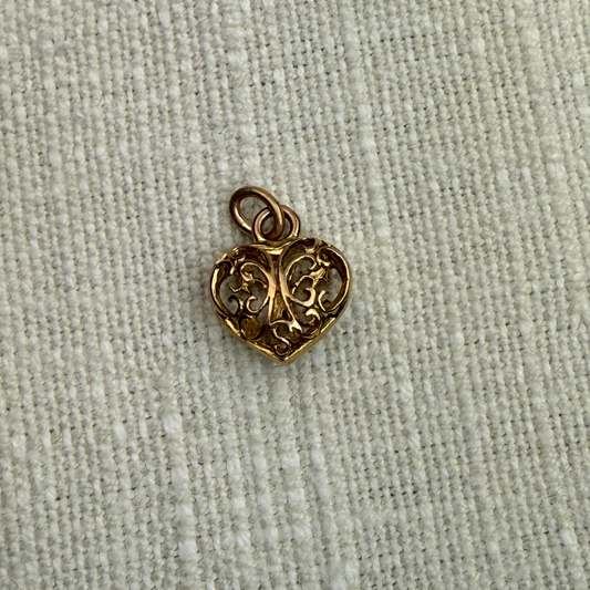 Gold heart-shaped pendant on a textured beige fabric background