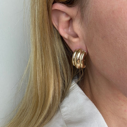 ribbed gold earrings in a ear of a women with blonde hair and white collar