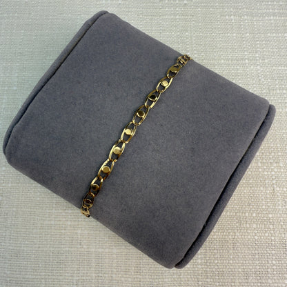 Image of fancy link gold chain on a grey pillow.