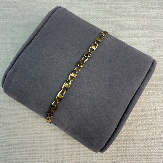Image of fancy link gold chain on a grey pillow.