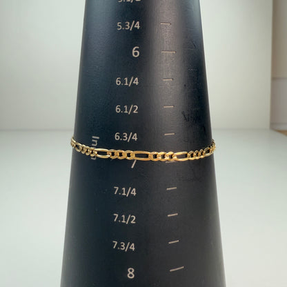 Figaro link bracelet displayed on a black mandrel with white inch markings, measuring 7 inches.