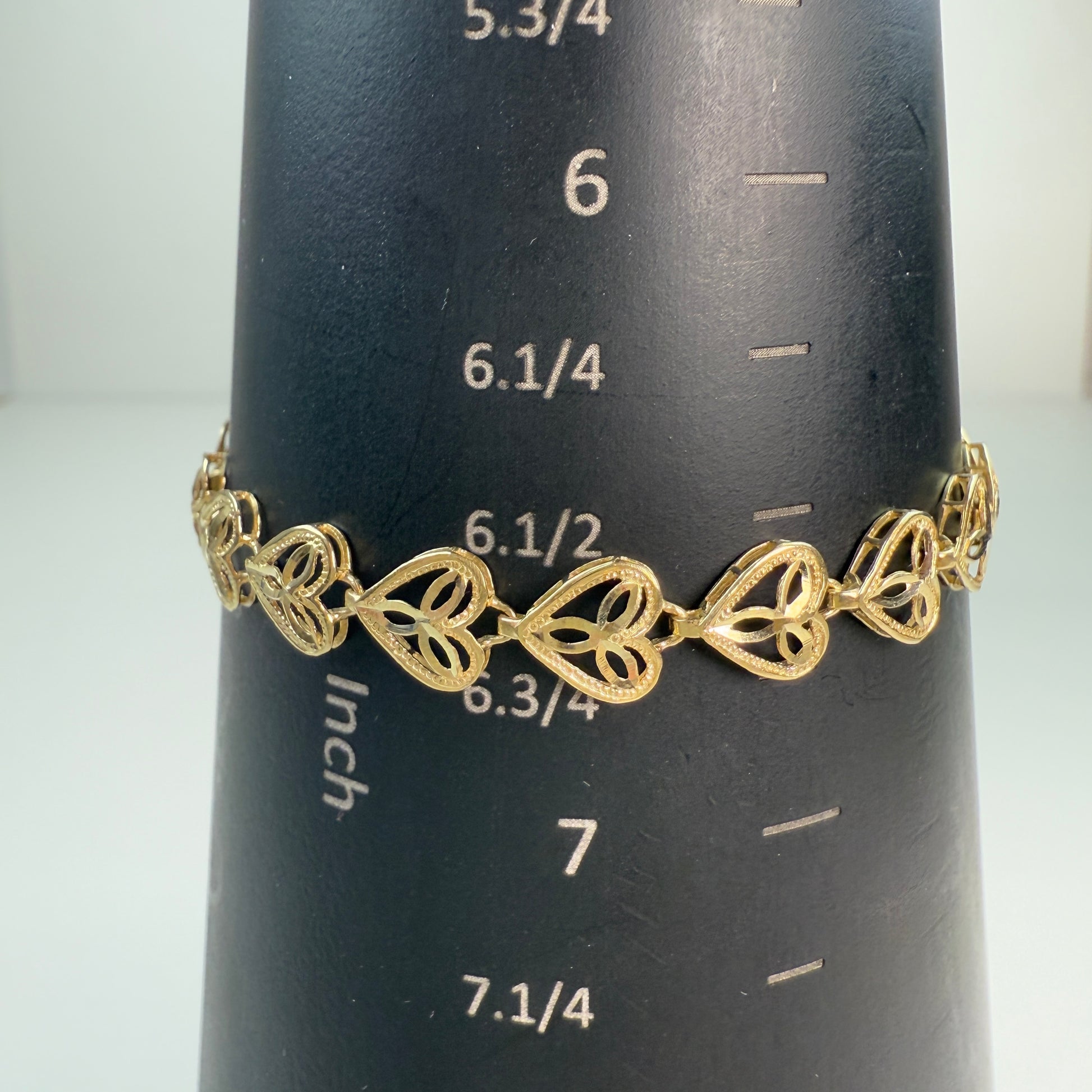 Gold heart fligree link bracelet on black mandrel with white markings shows it is 6.626"