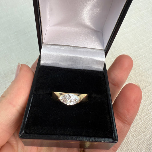 Gold ring with a diamond in a black box held by a hand.