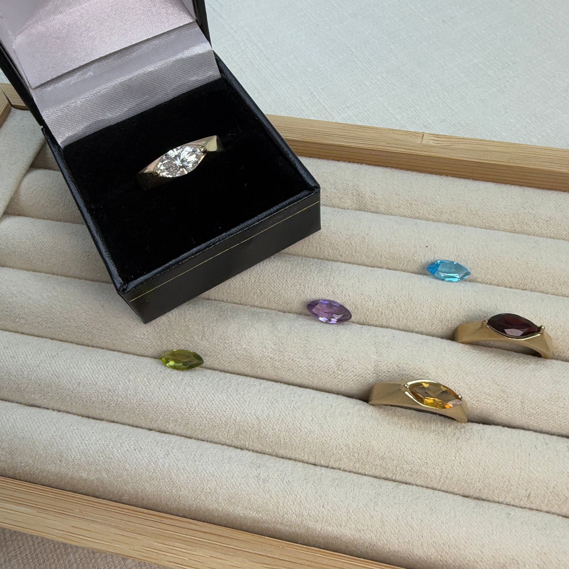 Jewelry box with a diamond ring on a display of other rings with gemstones.