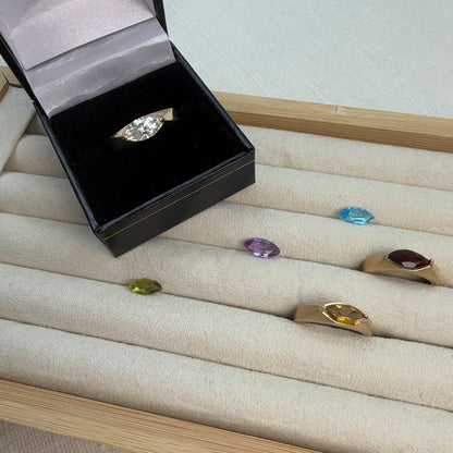 Jewelry box with a diamond ring on a display of other rings with gemstones.