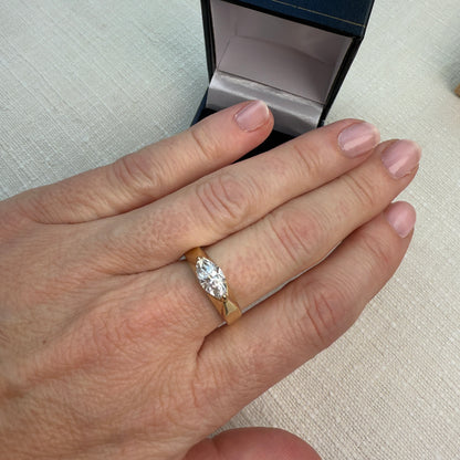 Hand wearing a diamond ring with an open jewelry box in the background
