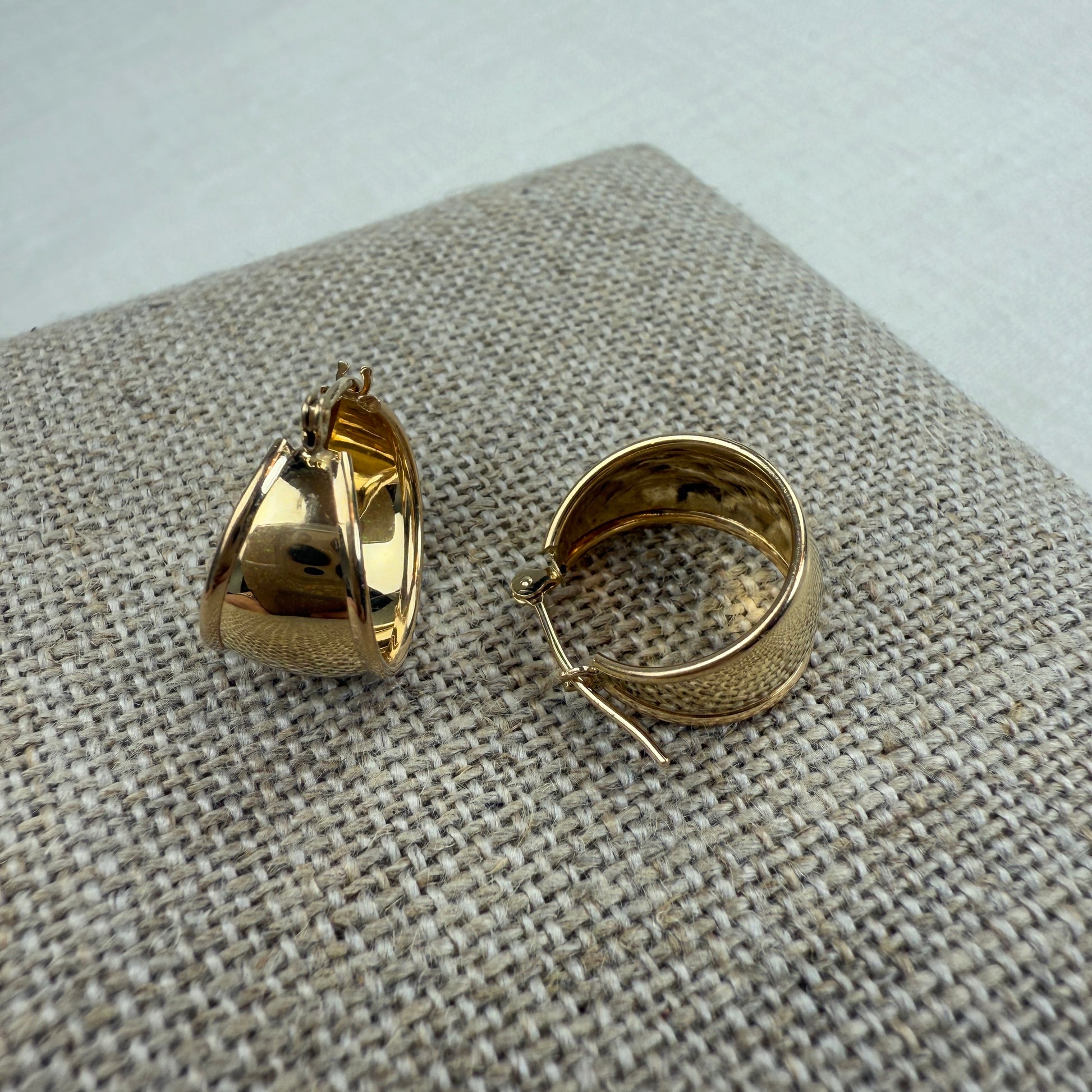 Gold hoop earrings on a textured fabric surface