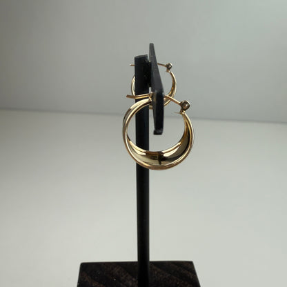 Gold hoop earrings on a black stand against a gray background