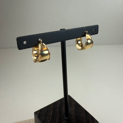 Gold hoop earrings on a black stand against a gray background