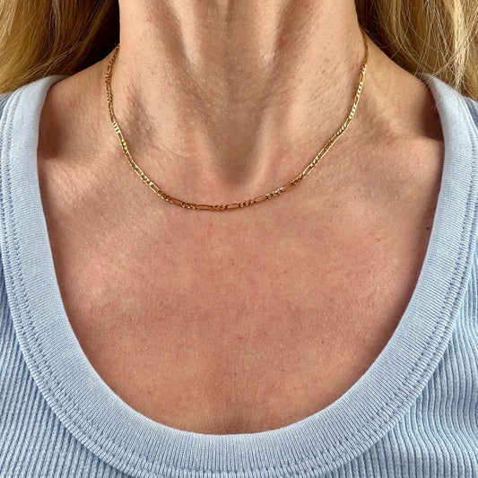 Gold necklace on a person wearing a light blue top