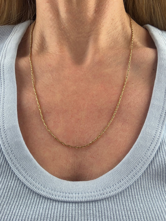 18K gold chain on a women's neck with a blue shirt