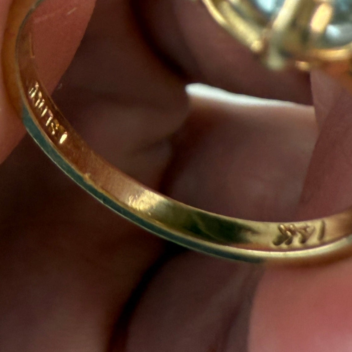 Gold ring with an aquamarine gemstone showign 14K stamp and hallmarks with fingers