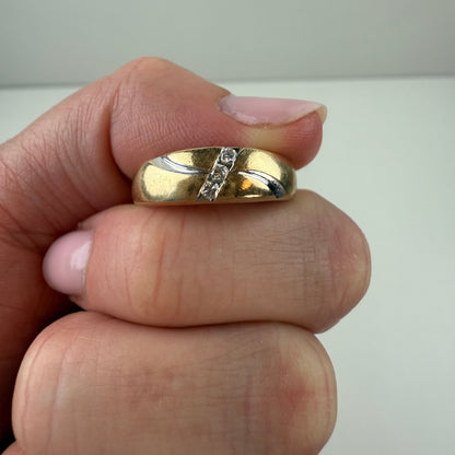 Gold ring with a diamond on a finger against a neutral background