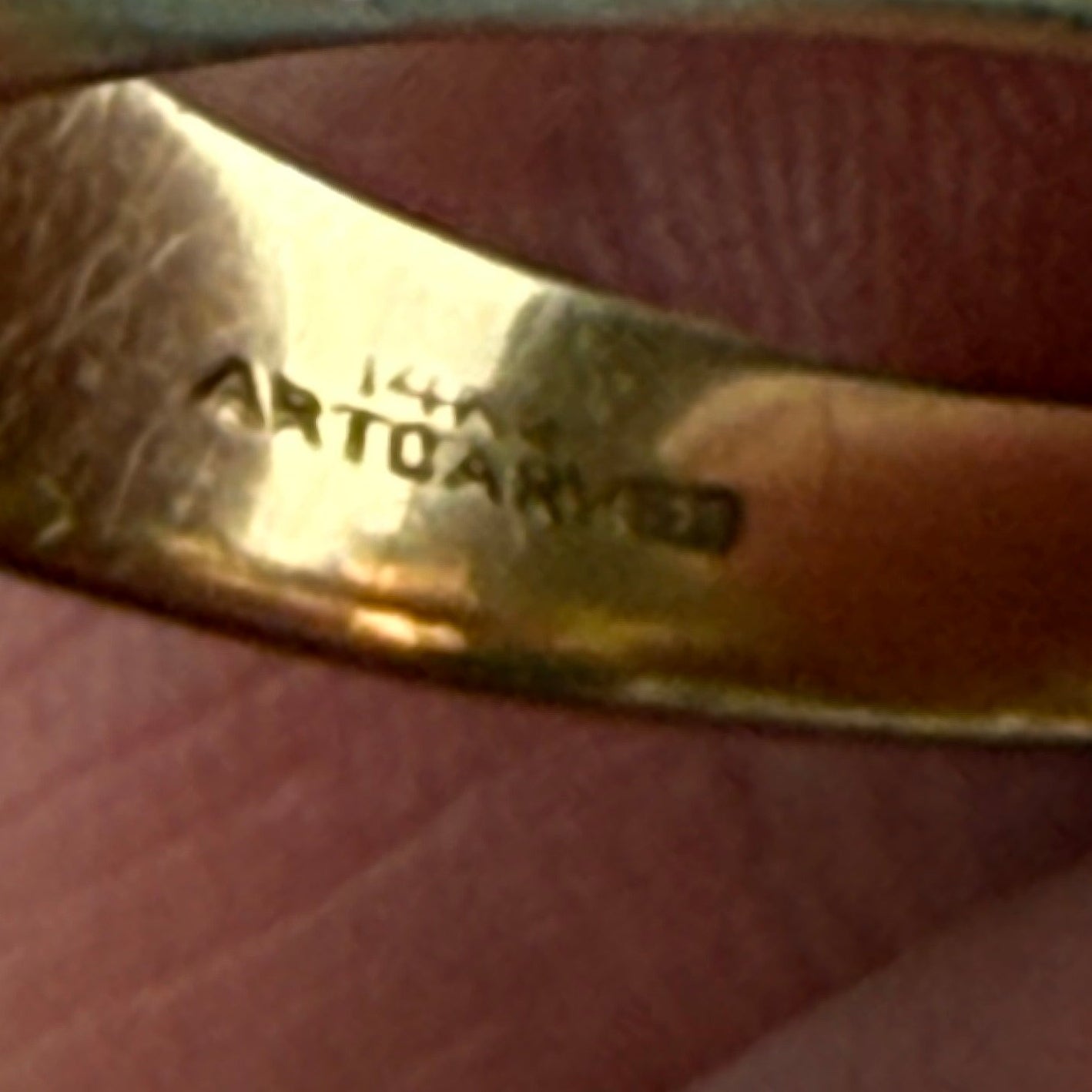 Gold ring being held by a finger with 14K stamp and Artcarved branding.