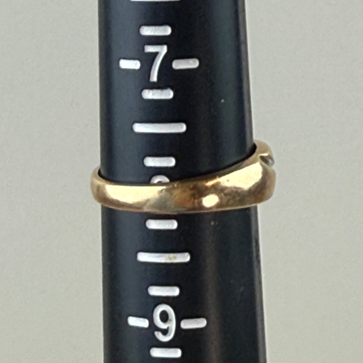 Gold ring on a black measuring tool with white markings