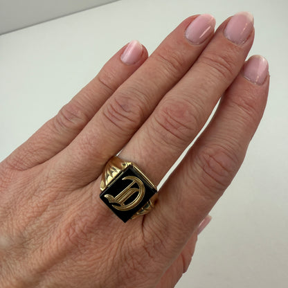 Hand wearing a gold and black ring on a light background