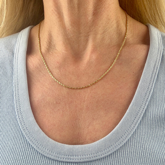 Gold necklace worn by a person with a light gray top
