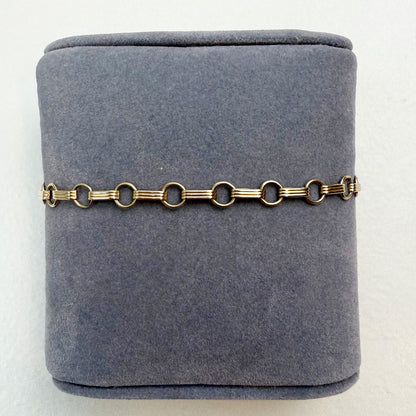 Gold chain bracelet on a gray velvet jewelry box