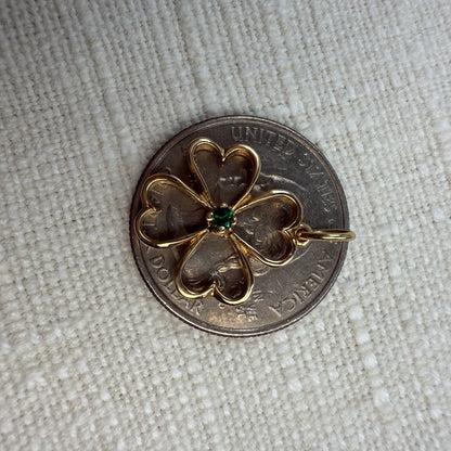Gold four-leaf clover pendant on a quarter, showing it is smaller than a quarter