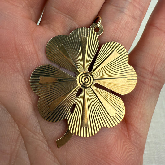 Engine turned vintage four-leaf clover pendant held in a hand