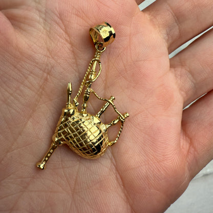 Gold bagpipes pendant held in a hand