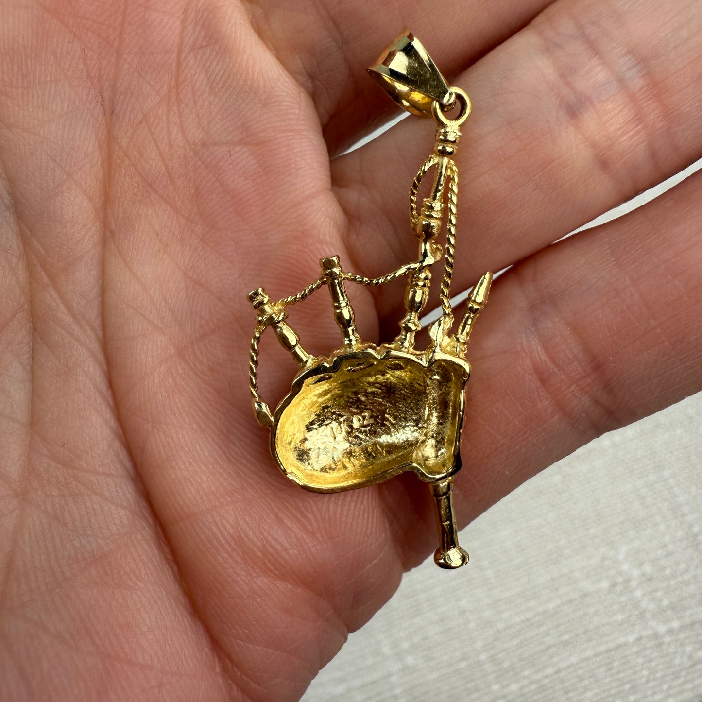 Back of old bagpipes pendant held in a hand