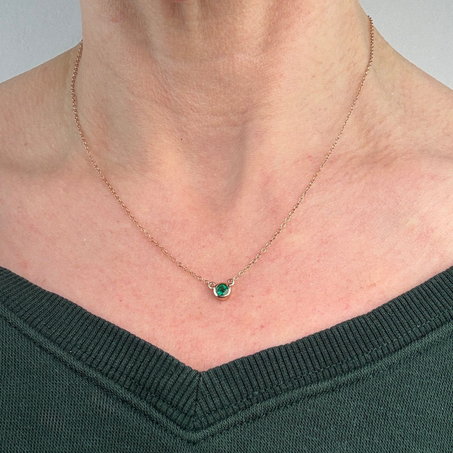Necklace with an emerald gemstone pendant worn by a person