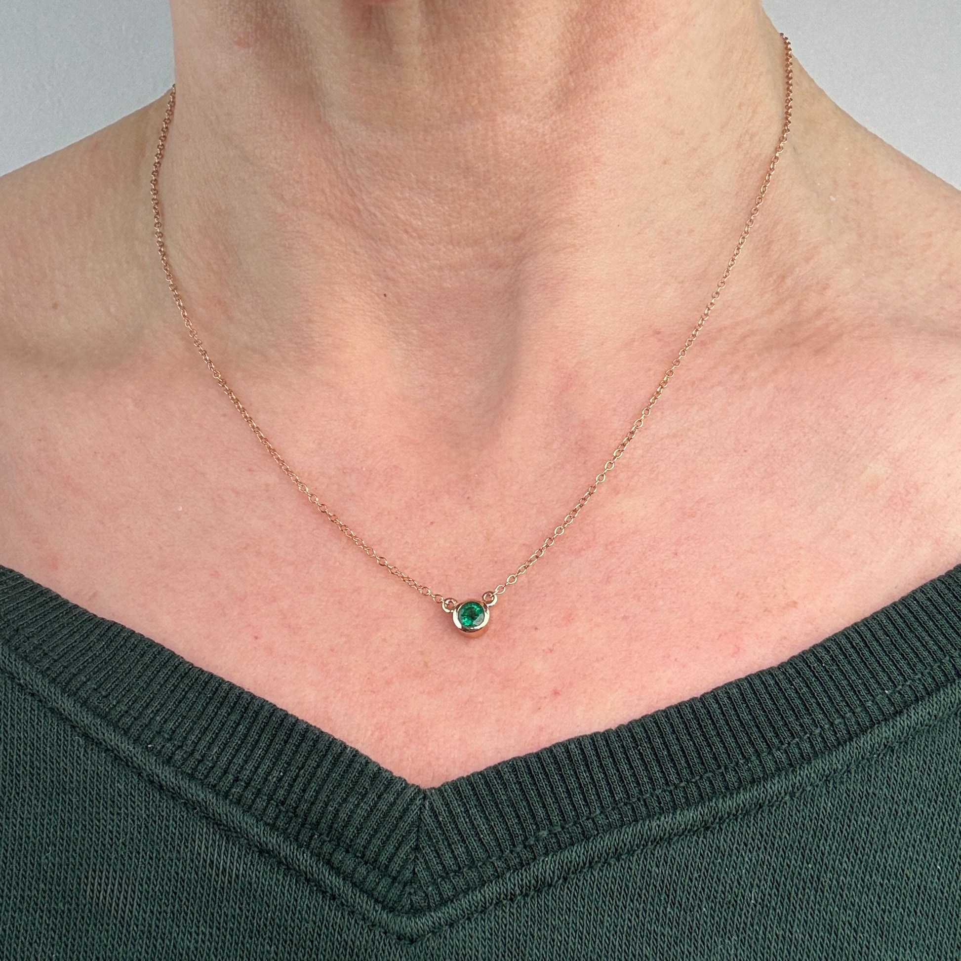 Necklace with an emerald gemstone pendant worn by a person