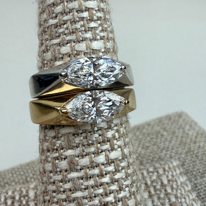 White gold and yellow gold rings with a 1-carat lab marquise diamond ring on a textured ring stand together. 