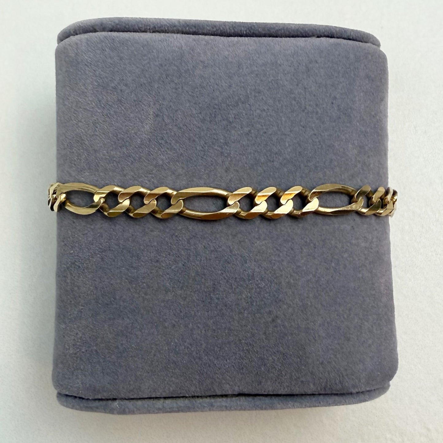 Gold chain bracelet on a gray cushion