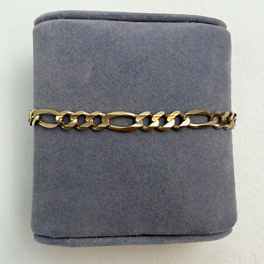 Gold chain bracelet on a gray cushion