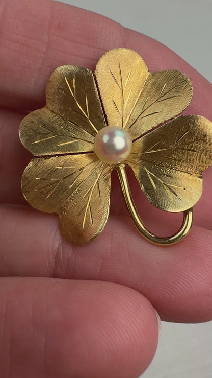 Video of the gold textured four leaf clover and pearl in hand moving slowly. 