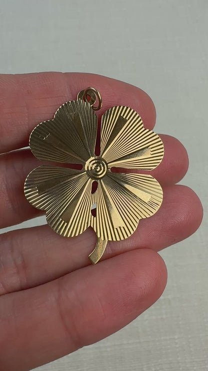 Video of an engine turned vintage four-leaf clover pendant held in a hand and slowly moving. 