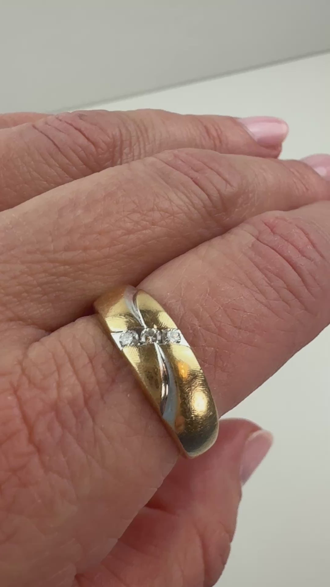 two-tone gold ring with three diamonds and wave pattern slowly moving on hand. 
