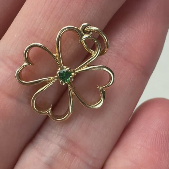 Video of the gold and emerald four leaf clover on a hand moving slowly. 