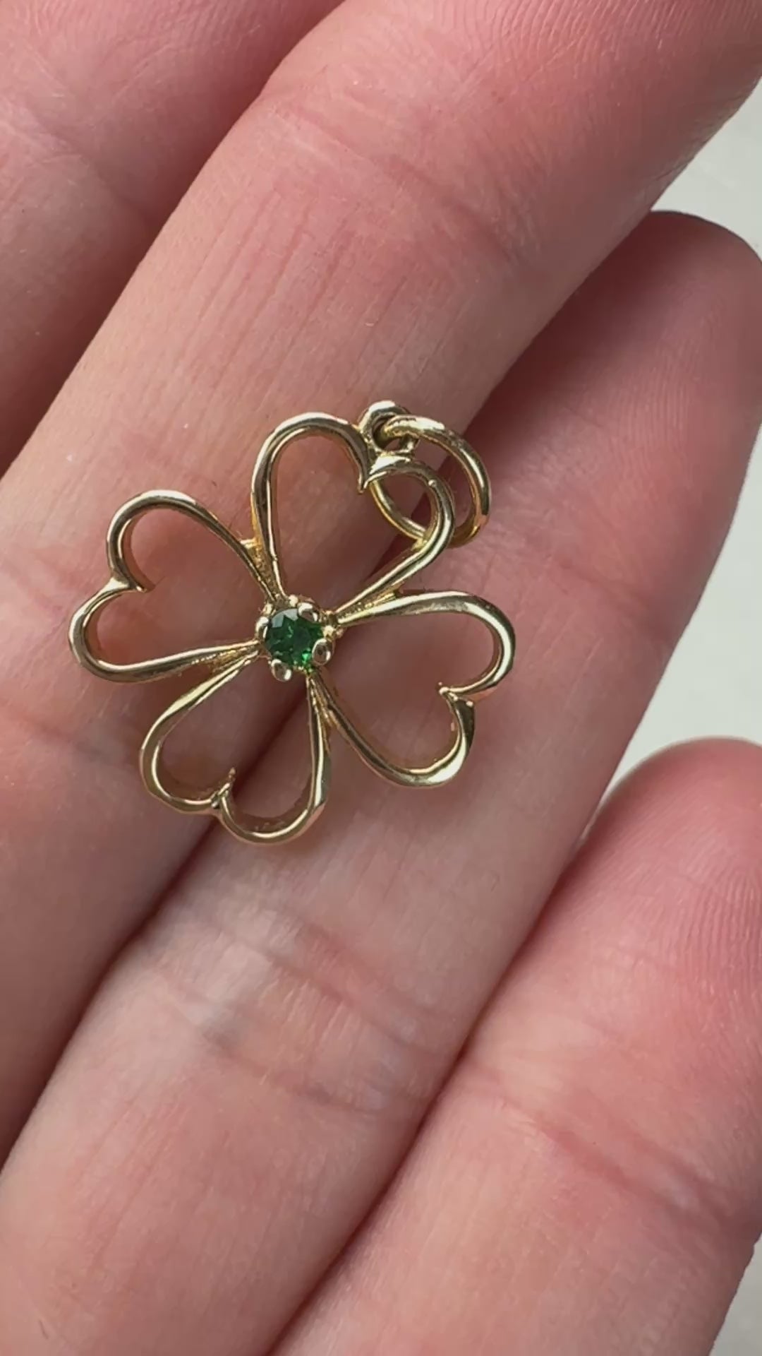 Video of the gold and emerald four leaf clover on a hand moving slowly. 