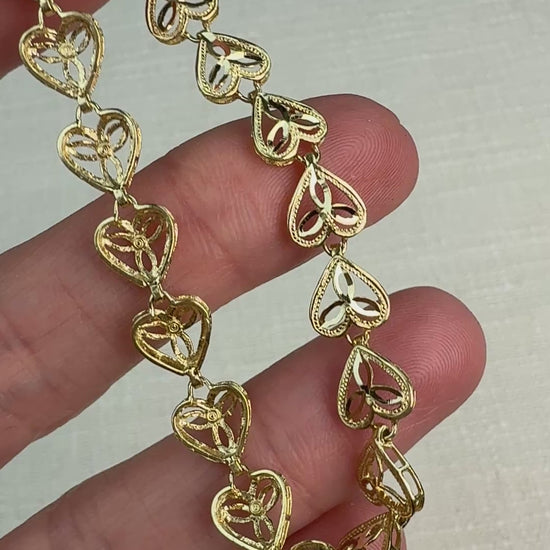 Short video of a gold heart filigree bracelet gently moved in hand to show shine.