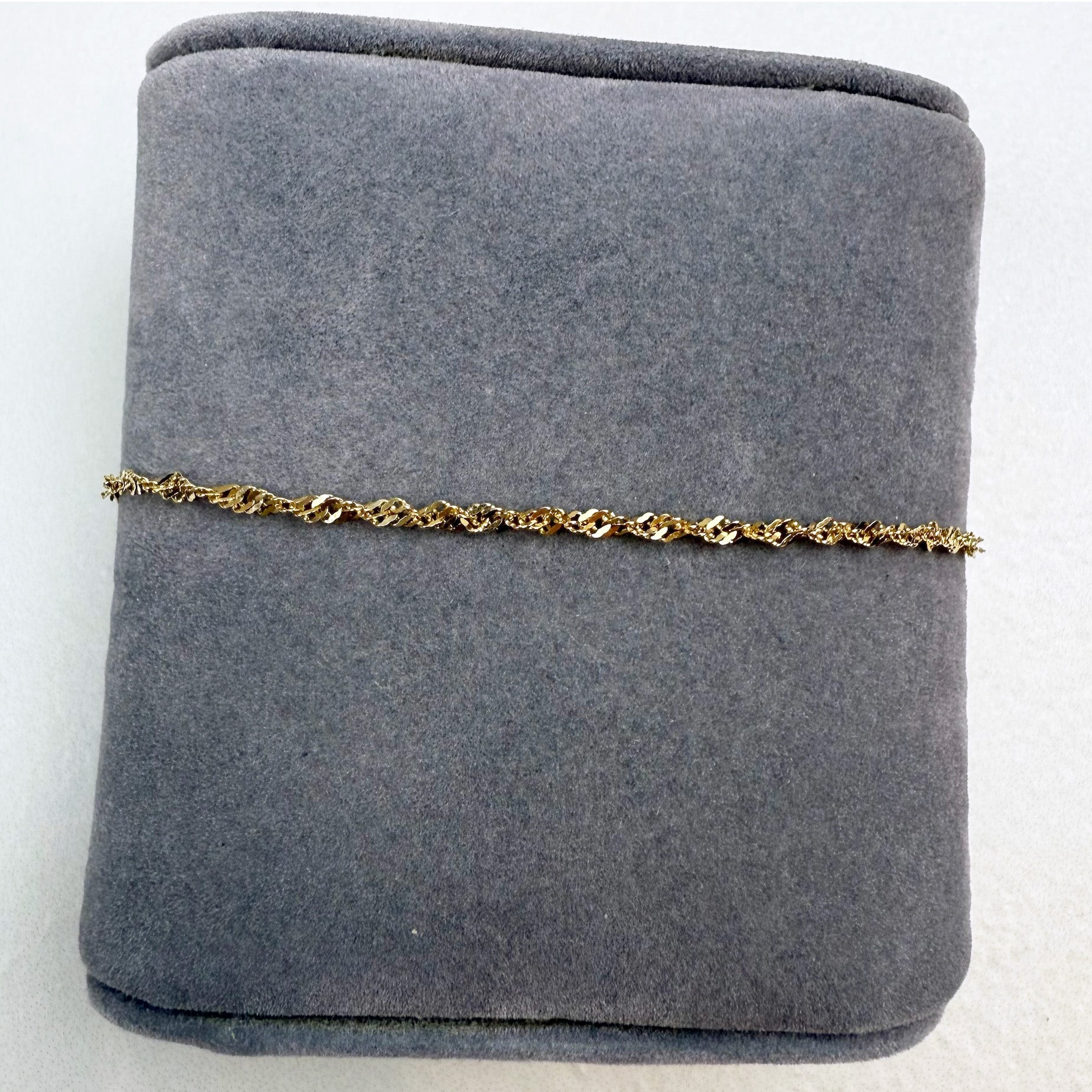 Gold chain bracelet on a gray jewelry display box