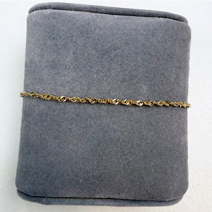 Gold chain bracelet on a gray jewelry display box